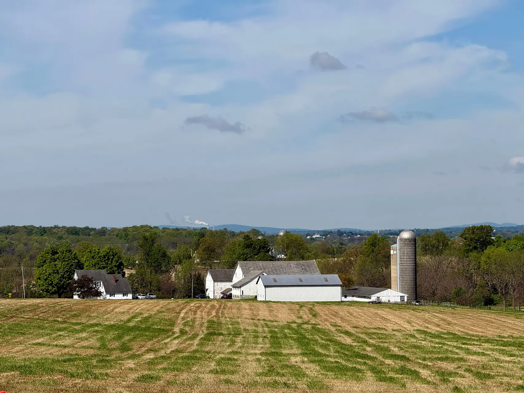 Rolling Lancaster County farmland with a white barn and a silo under a cloudy sky
